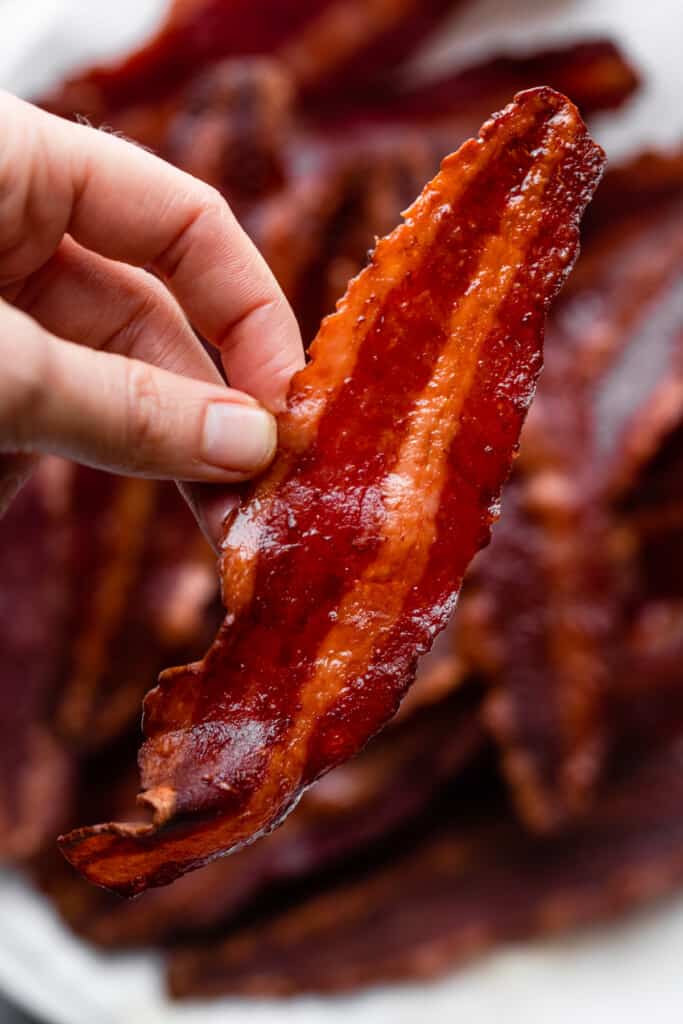 one slice of Air Fryer Turkey Bacon being held up by hand