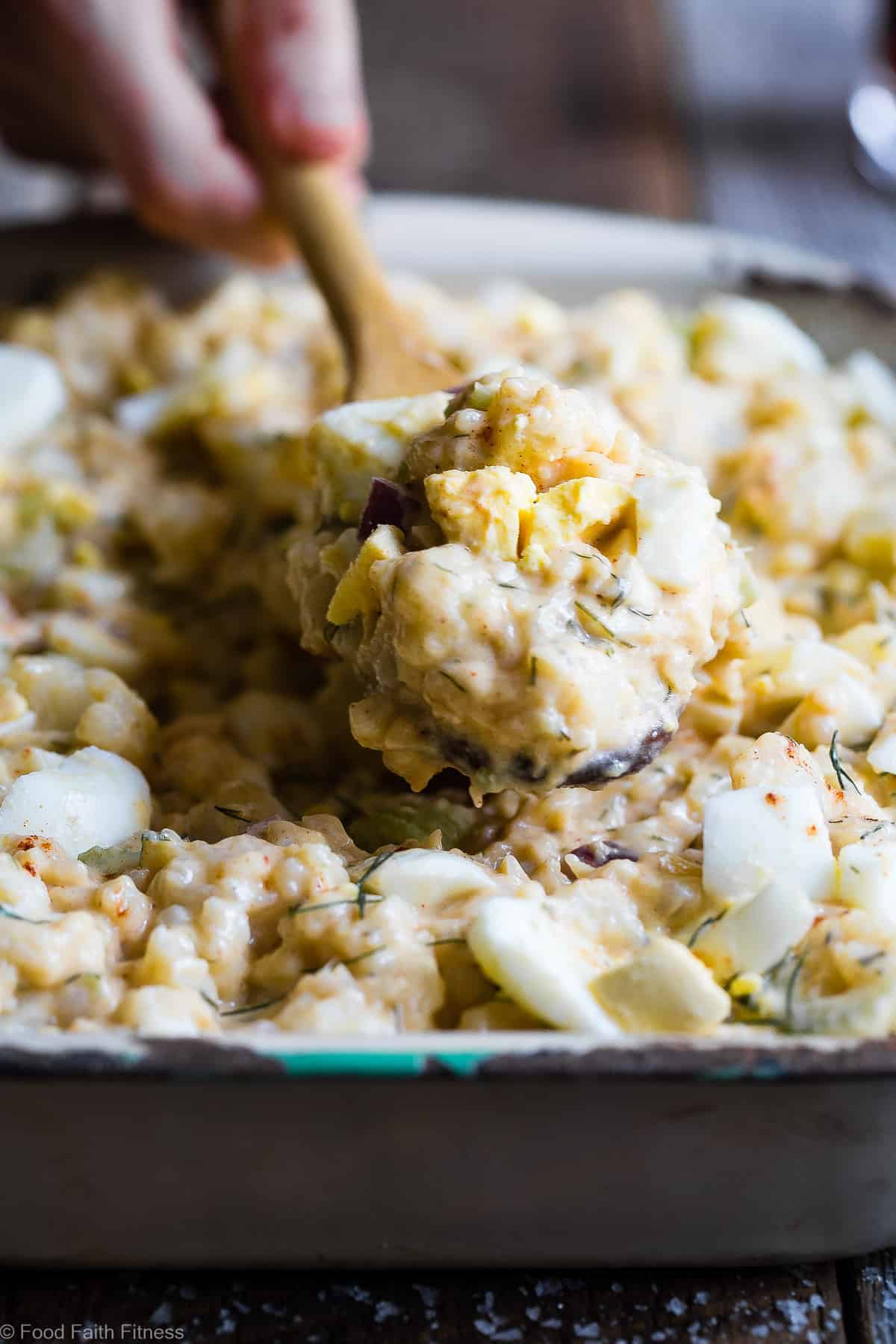 side view of Cauliflower Potato Salad in a serving dish with wooden spoon